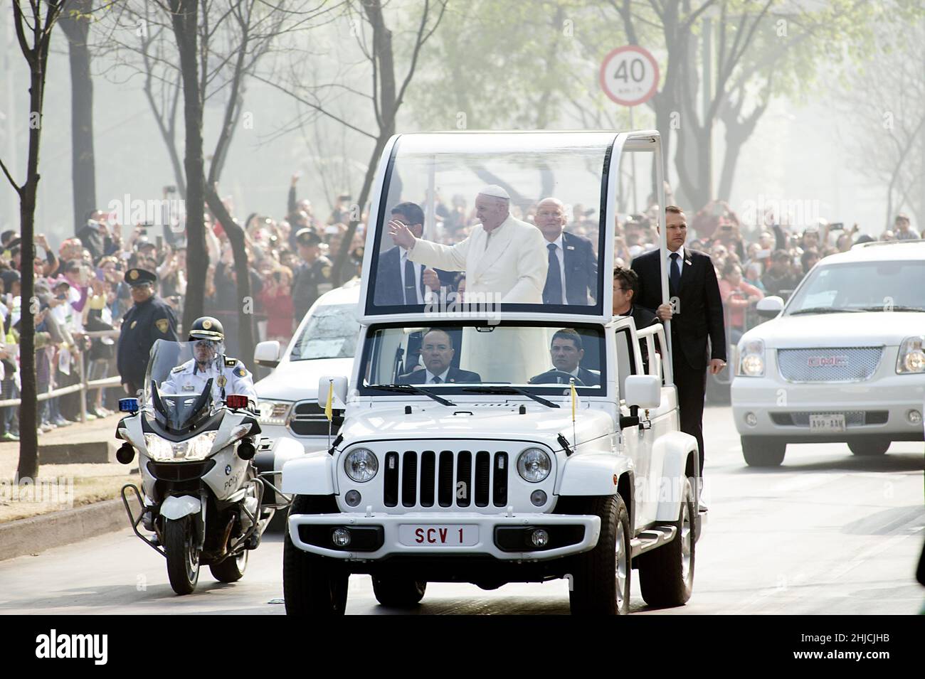 February 14, 2016; Mexico City, Mexico. Pope Francis riding in a Chrysler Jeep Wrangler popemobile speeds past crowds of waving Mexicans along a major avenue in Mexico City during his second full day of activities in the Mexican capital. Pope Francis spent 5 days in Mexico visiting cities all across Mexico recently torn by a brutal drug war, corruption, and economic problems. Stock Photo