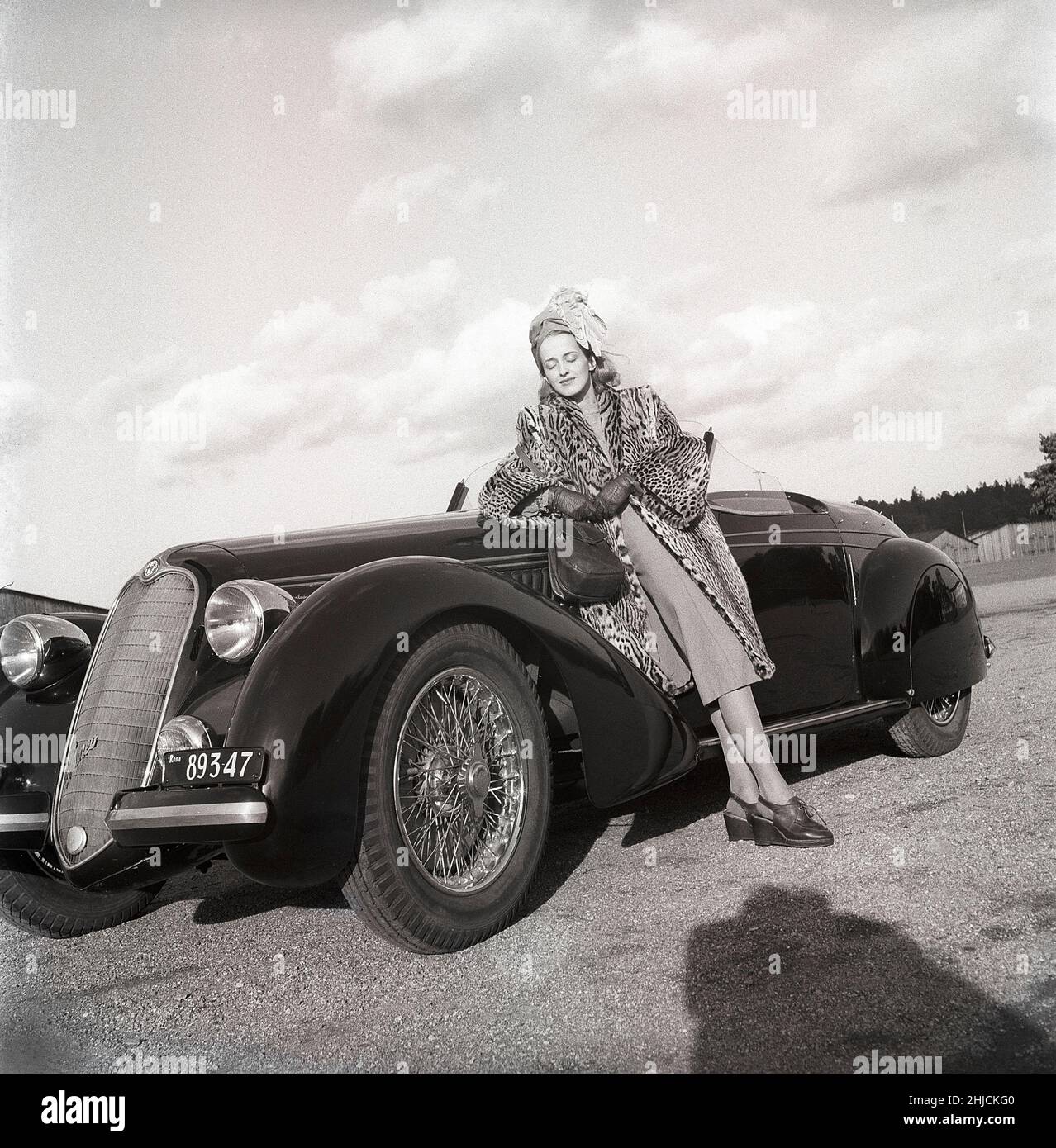 Women's fashion in the 1940s. A young woman in a typical 1940s outfit. A matching skirt and jacket with a leopard patterened coat . The car is a italian sports car from the car manufacturer Alfa Romeo.   Sweden 1946. Kristoffersson Ref X1-3 Stock Photo