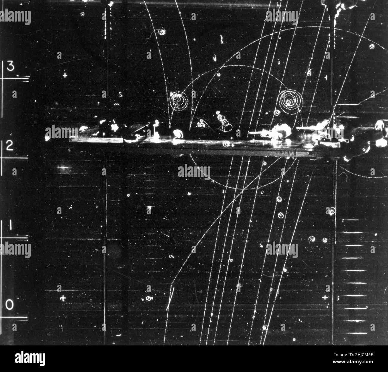 Bubble chamber event: Particles passing through lead shielding. November 17, 1964. Bubble Chamber-1408. Lead shielding refers to the use of lead as a form of radiation protection to shield people or objects from radiation so as to reduce the effective dose. Lead can effectively attenuate certain kinds of radiation because of its high density and high atomic number; principally, it is effective at stopping gamma rays, and x-rays. A bubble chamber is a vessel filled with a superheated transparent liquid (most often liquid hydrogen) used to detect electrically charged particles moving through it. Stock Photo