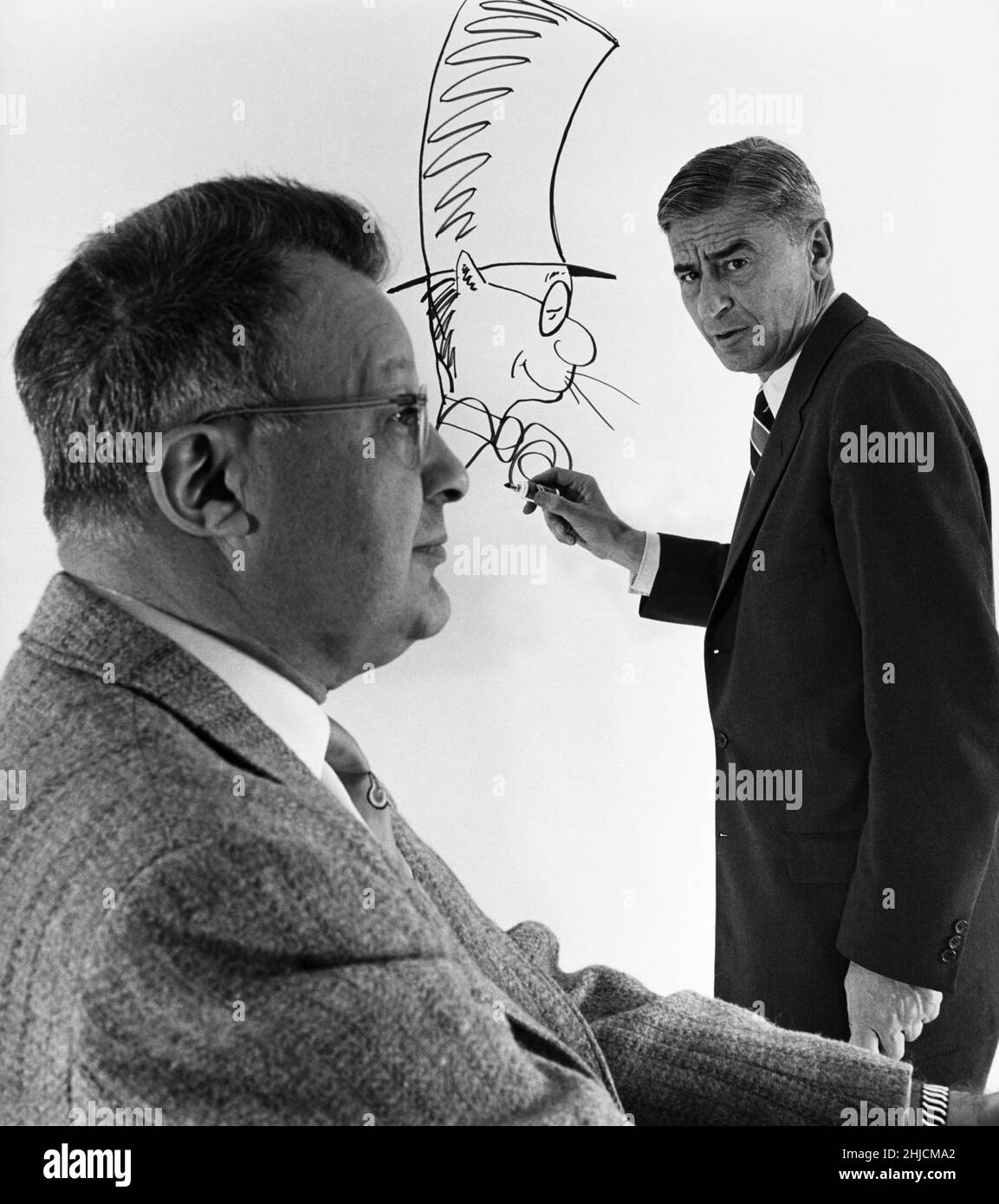 Dr. Seuss (1904-1991) sketching Clifton Fadiman (1904-1999) as the Cat in the Hat. Clifton Fadiman was an editor, author and well-known radio and television personality. He was the radio quiz show host of 'Information Please!', chief editor at Simon & Schuster, and literary editor of The New Yorker magazine in the 1930s and 1940s, among other employments. Dr. Seuss, whose real name was Theodor Seuss Geisel, was the author and illustrator of many beloved children's books, including 'Green Eggs and Ham,' 'The Sneetches' and 'The Cat in the Hat.' Stock Photo