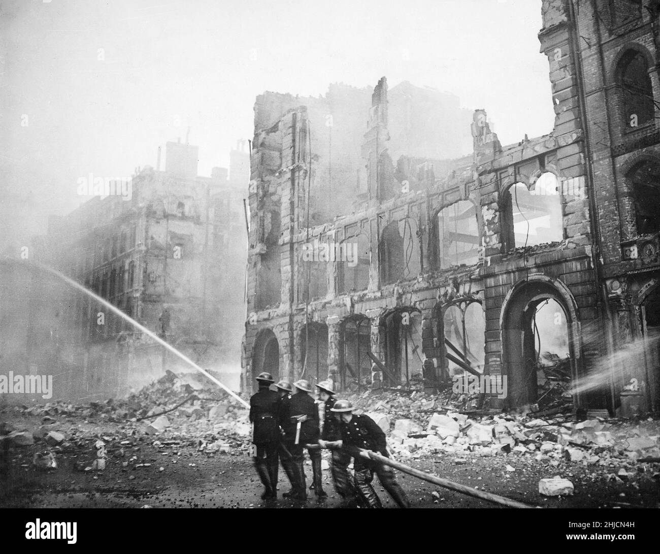 Firemen at work in a bomb-damaged street in London after a Saturday night Blitz raid, circa 1941. The Blitz was a German bombing campaign against the United Kingdom in 1940 and 1941, during the Second World War. The term comes from Blitzkrieg, meaning 'lightning war' in German. Stock Photo