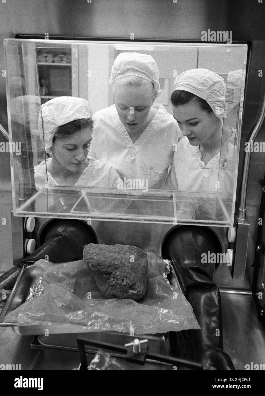 Brown and Root/Northrop technicians (left to right, Linda Tyler, Nancy L. Trent and Sandra Richards) in the Nonsterile Nitrogen Laboratory in the Lunar Receiving Laboratory (LRL) peer through glass at the rock that Apollo 14 crewmen brought back from the Fra Mauro area of the moon. February 24, 1971. Stock Photo