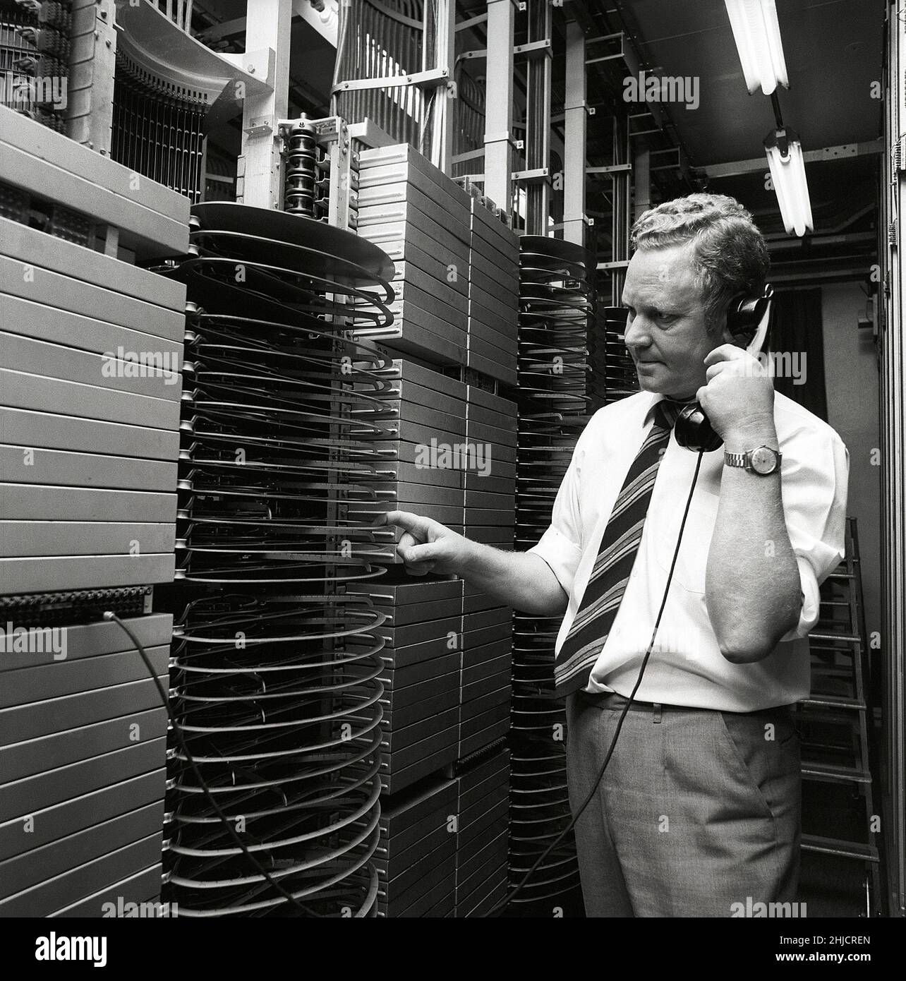 Telephony in the 1970s. A man in a room with an automatic switchboard connecting the calls through a mechanical device that connected the calling and receiving parts. The manufacturer is LM Ericsson. Sweden 1971 Kristoffersson ref ED Stock Photo