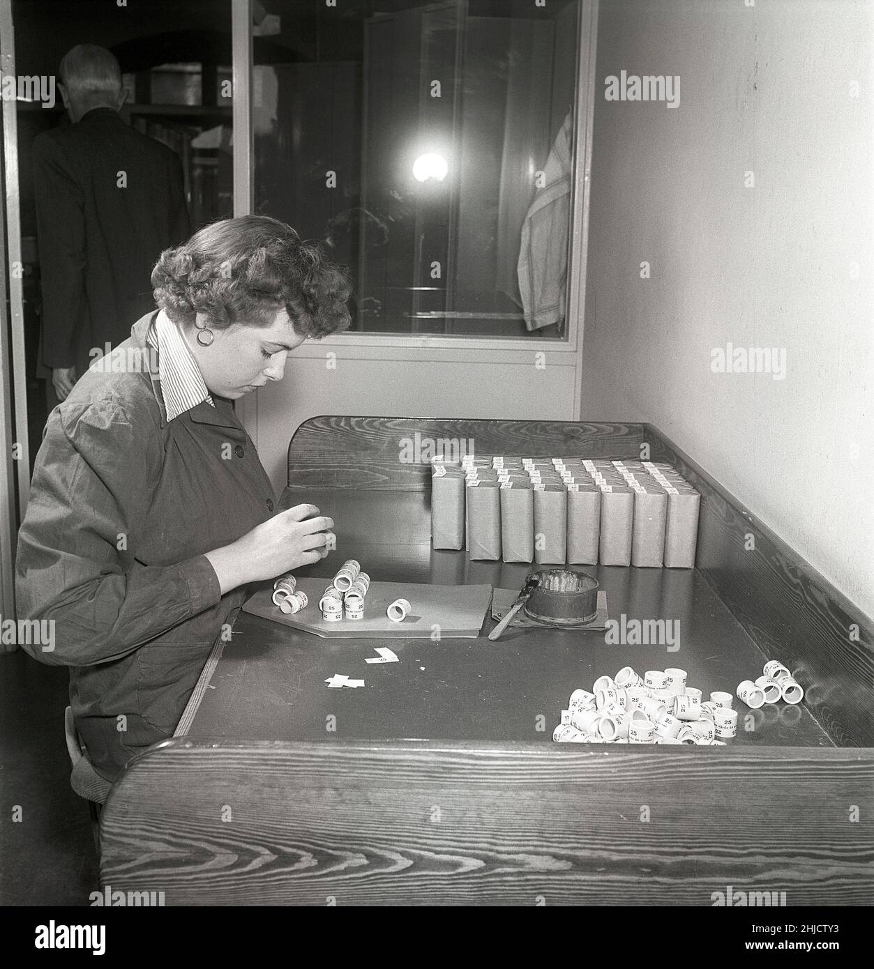 Producing postage stamps in the 1950s. A young woman at the swedish stamp printworks of the swedish post is making packages of  rolls of 100 or 500 stamps in each. Sweden 1951 Kristoffersson ref bc45-9 Stock Photo