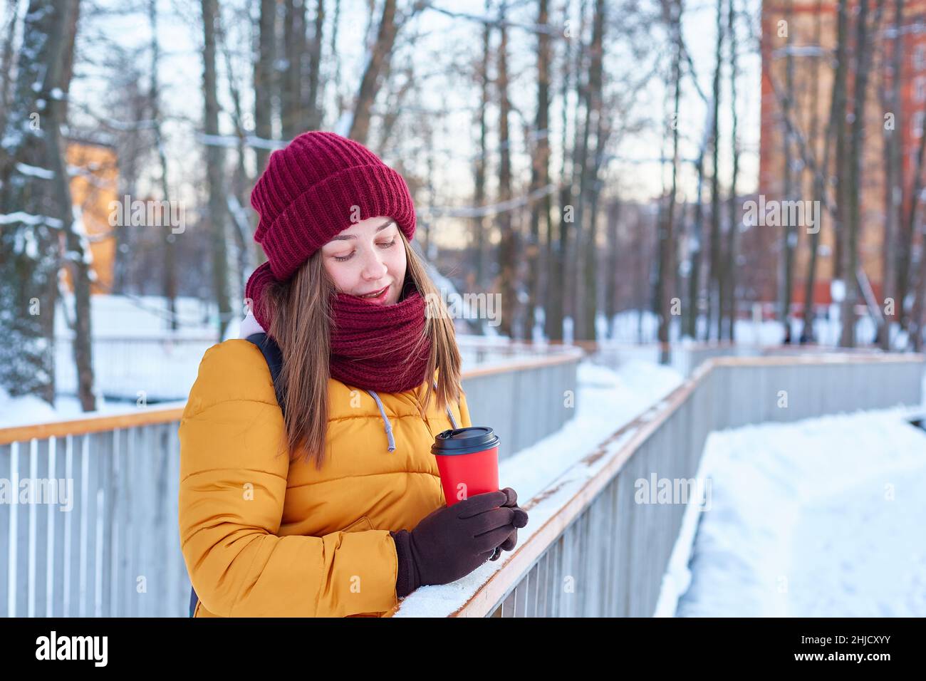young girl walks in a winter park with a cup of coffee in her hands Stock Photo