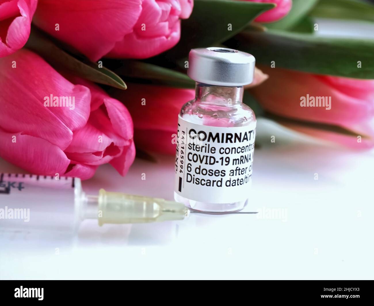 Comirrnaty vaccination ampoule with a syringe against covid-19 or Corona virus with flowers Stock Photo