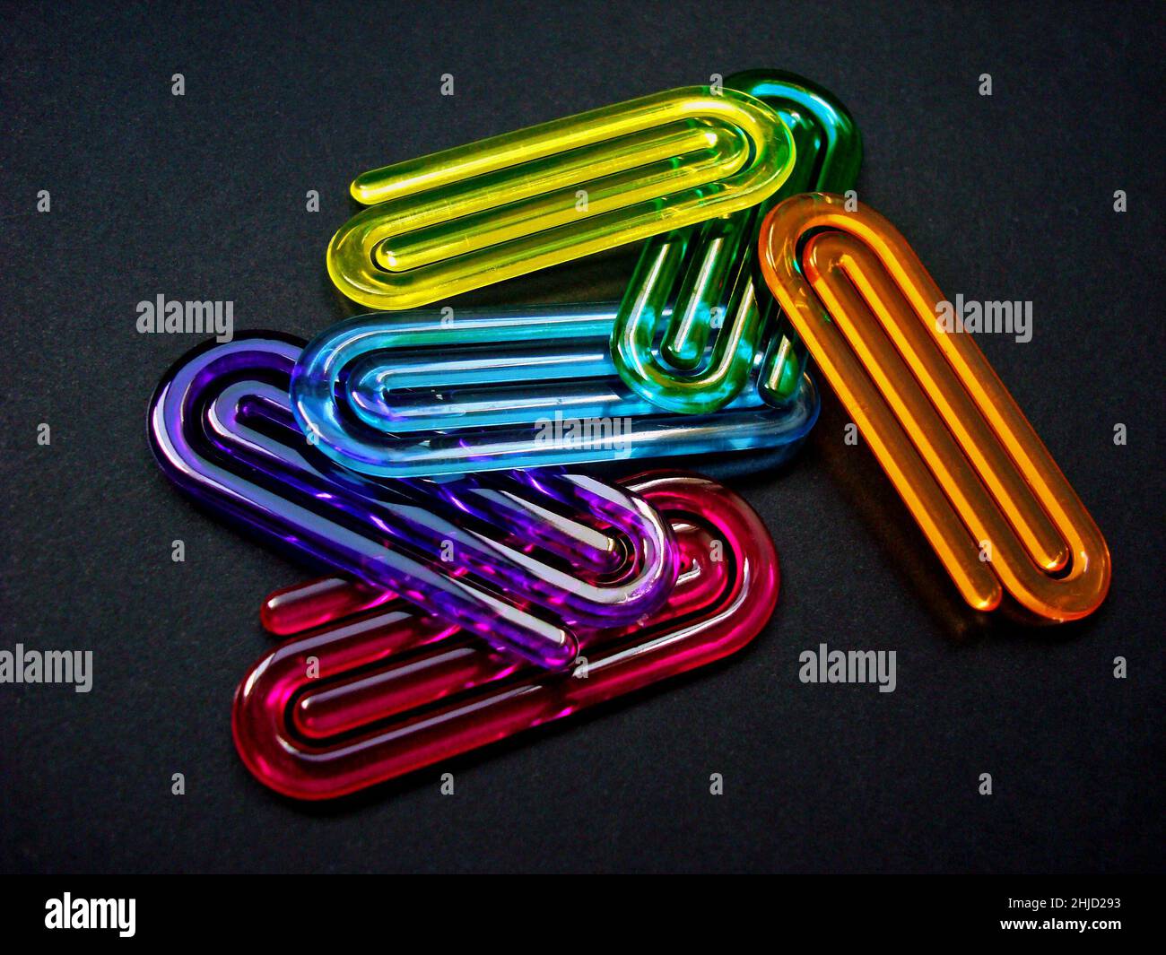 Acrylic paper clips on black background Stock Photo
