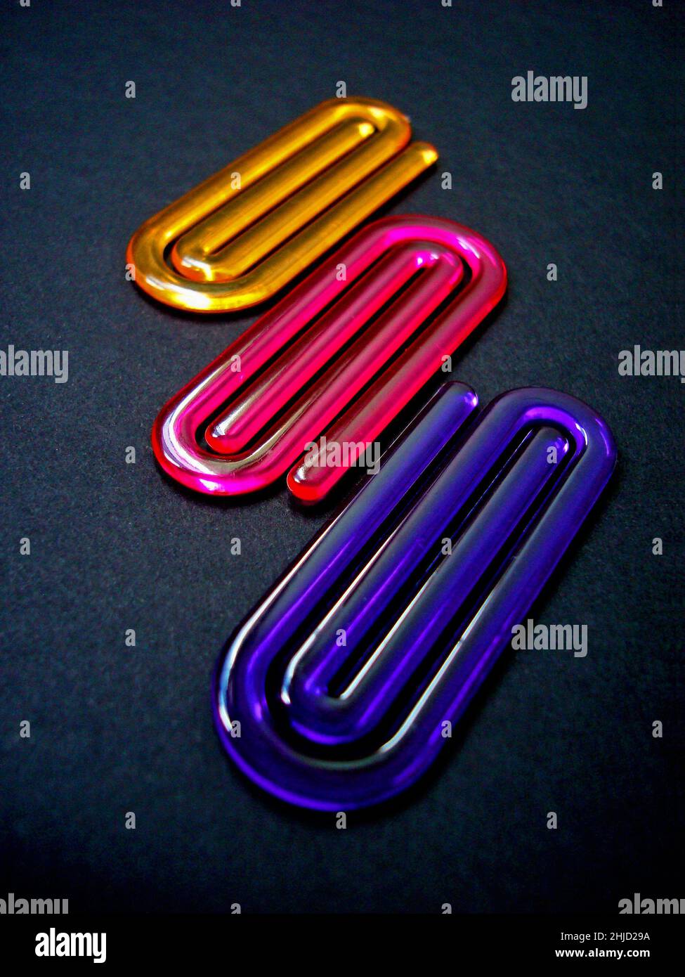 Acrylic paper clips on black background Stock Photo