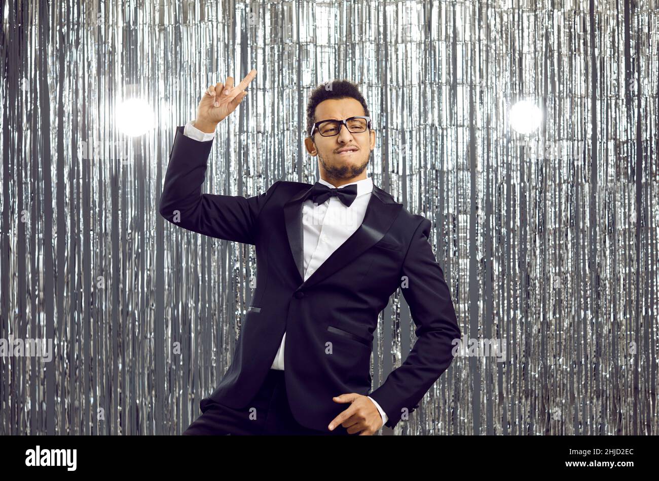Happy funny young man in an elegant suit and bowtie dancing and having fun at a party Stock Photo