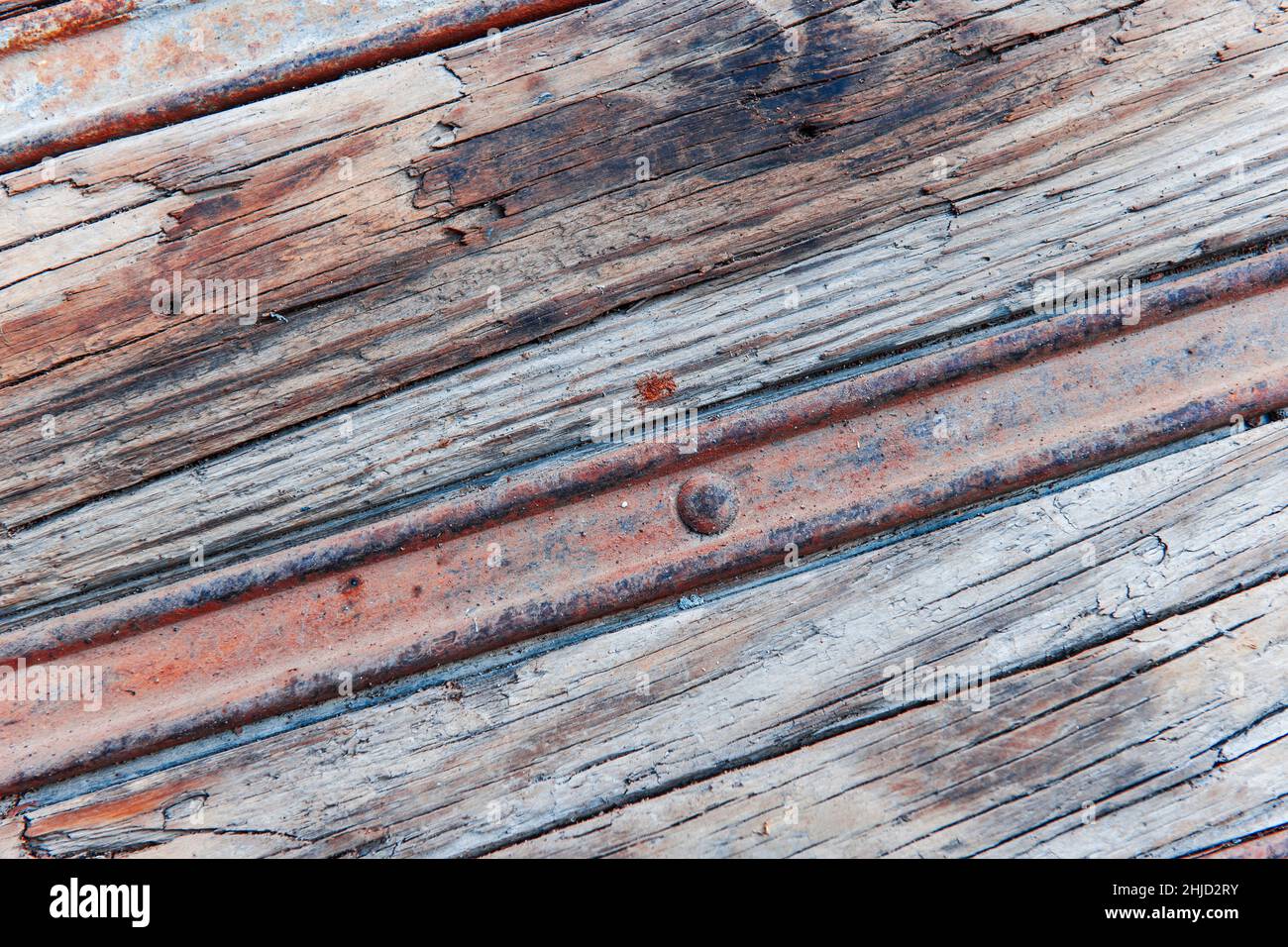 Format-filling view of a rusty metal rail in the weathered wood in an oblique view. Stock Photo