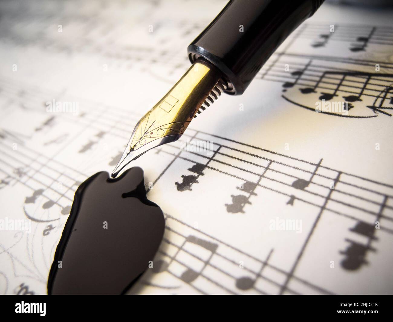 Close-up view of sheet music with fountain pen and black ink blot. Stock Photo