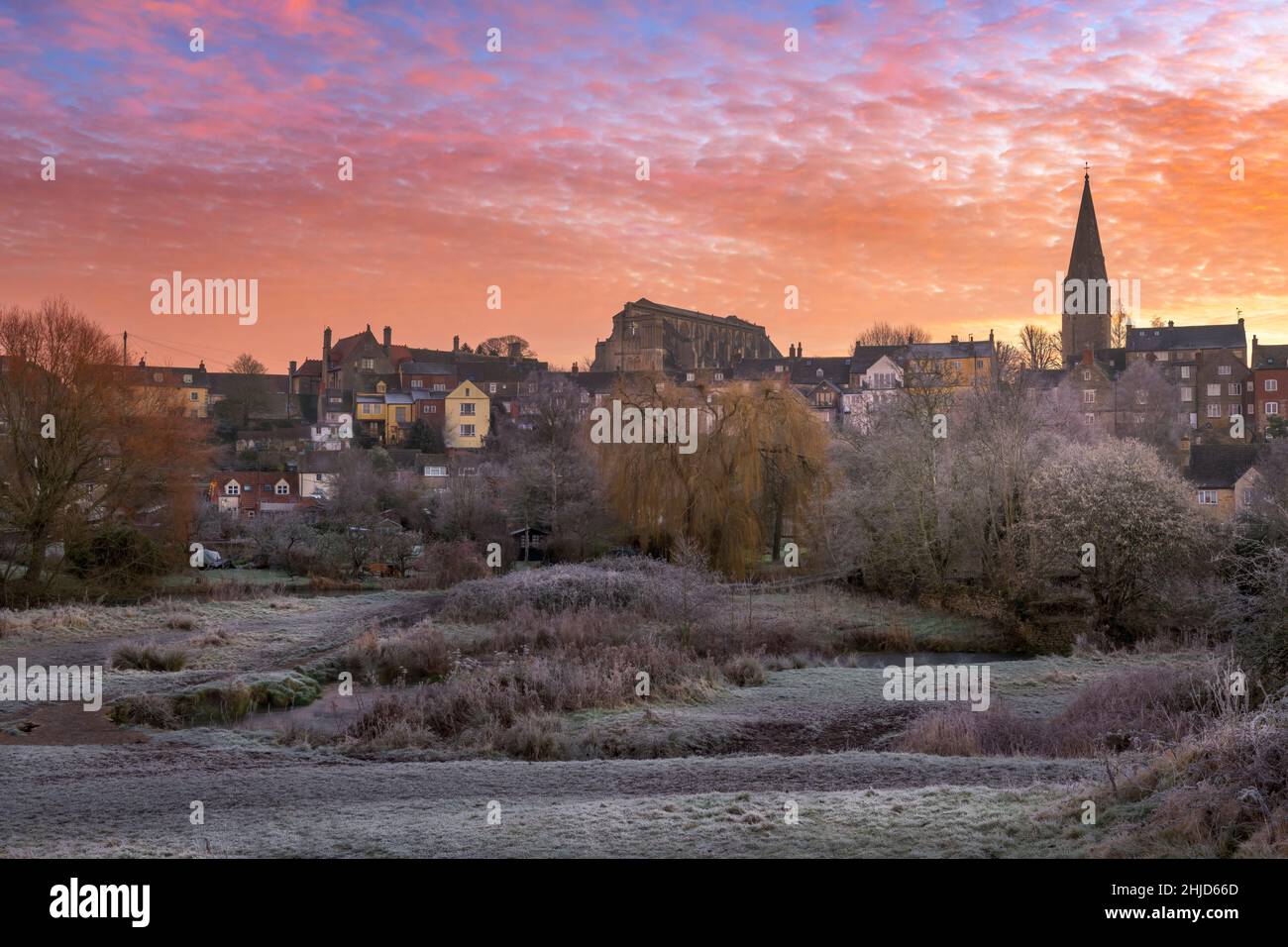 After a heavy overnight frost, at dawn the sky turns pink over Malmesbury and the ancient clapper bridge that leads towards the historic hillside mark Stock Photo