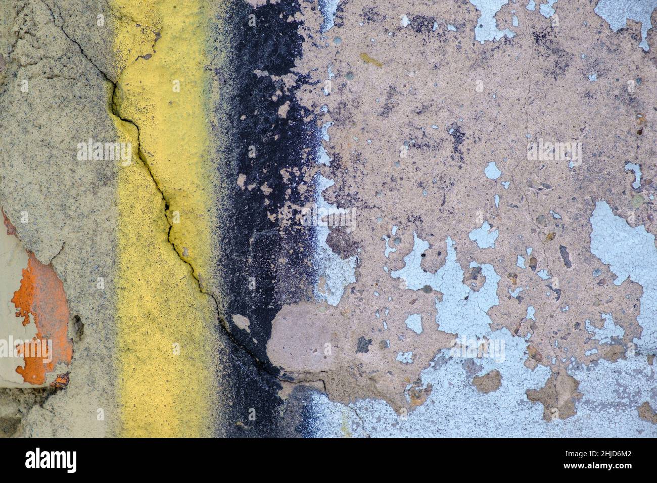 Old yellow blue black paint with cracks on red brick wall as background, texture, selective focus Stock Photo