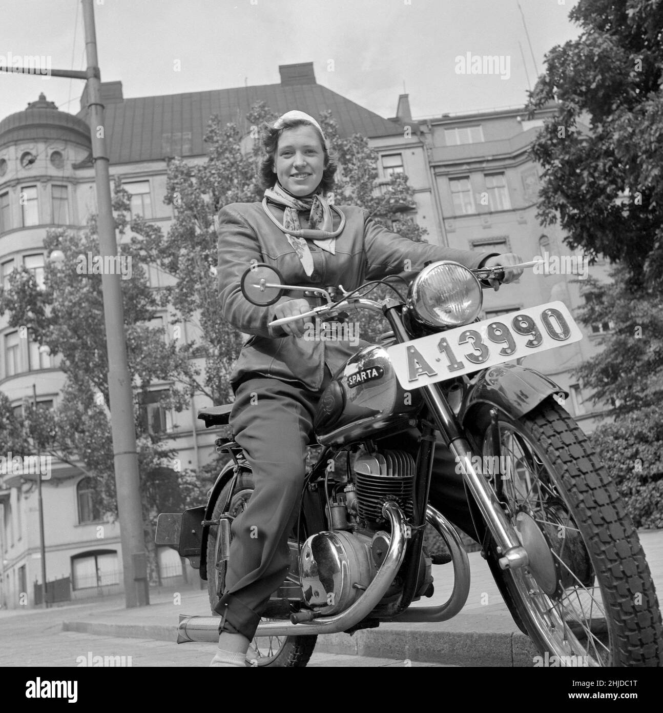 Motorcyclist in the 1950s. A young woman on her motorcycle dressed as the typical motorcyclist of the 1950s should with a leather jacket and a kidney belt. The motorcycle is a Sparta