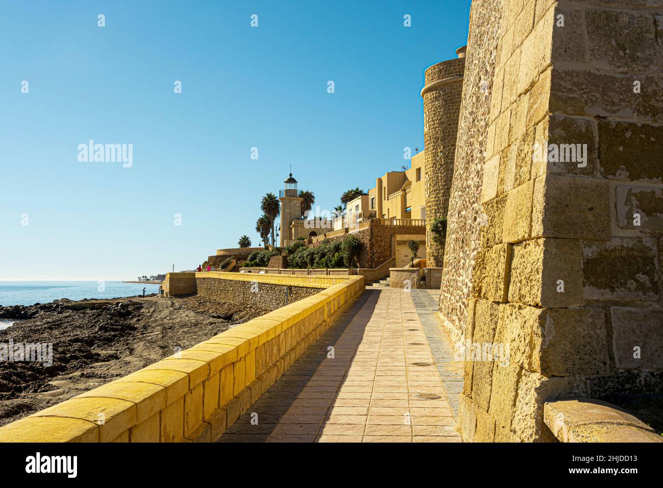 Path next to the walls of the old castle on the shores of the Mediterranean Sea in the city of Roquetas del Mar. Province of Almeria. Andalusia. Spain Stock Photo