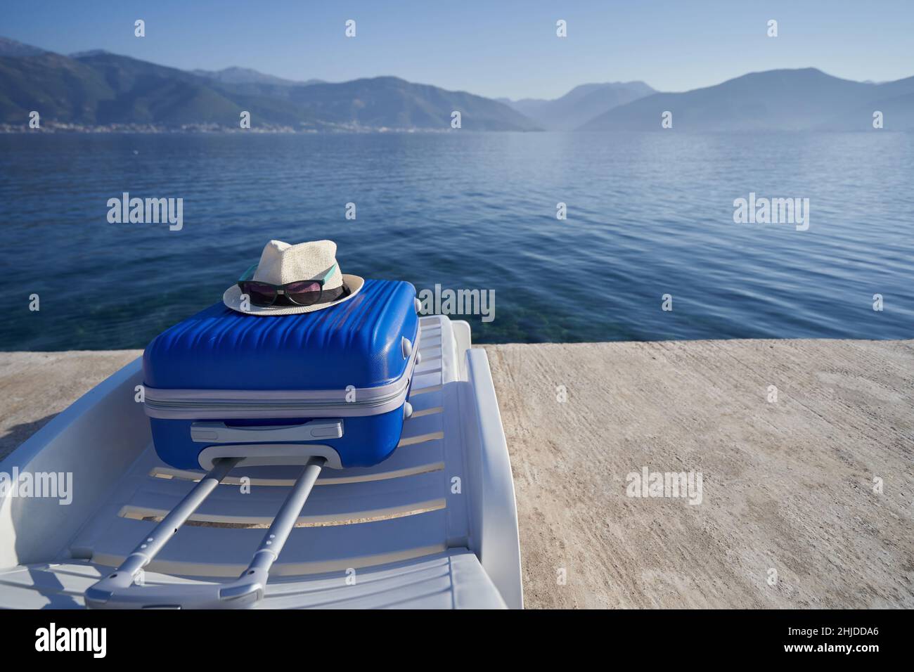 Blue suitcase on a sun lounger on the shore of the adriatic sea in Montenegro, travel concept Stock Photo
