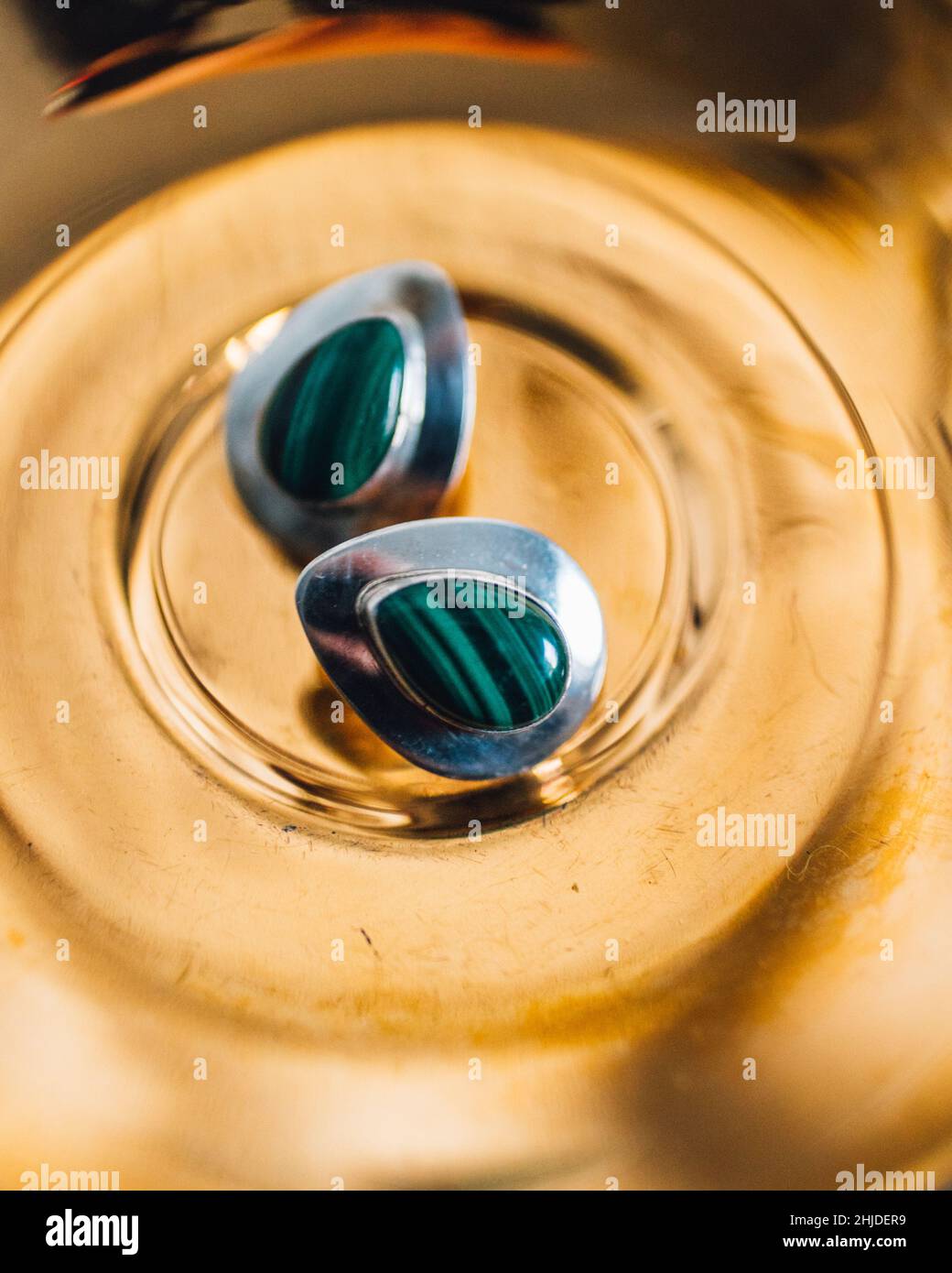 green malachite stone in sterling silver teardrop earrings on metallic gold saucer Stock Photo