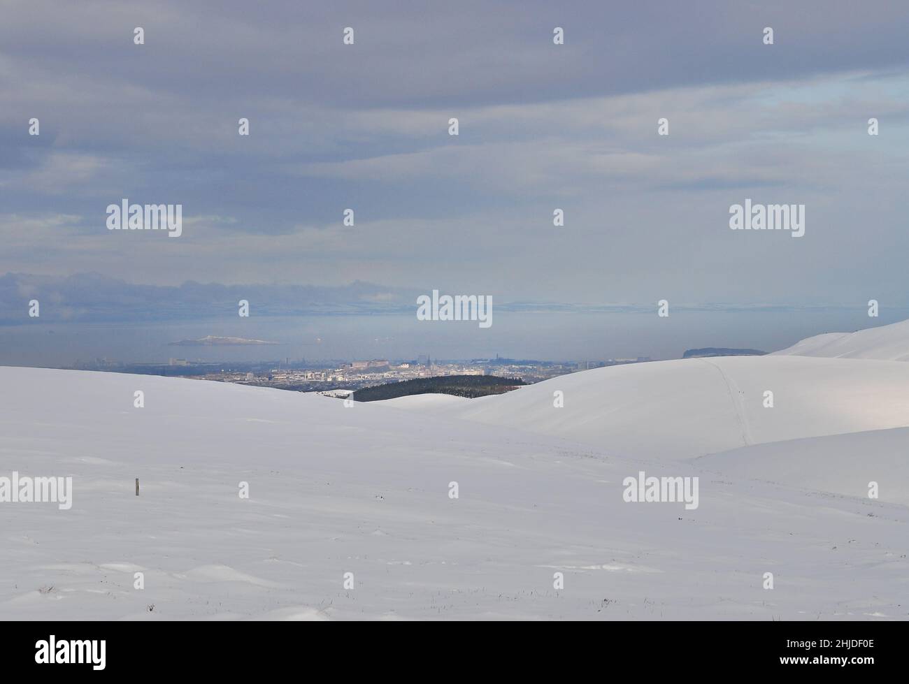 A snowy winter view of Edinburgh city centre from the Pentland hills, with the Firth of Forth, Inchkeith island and Fife in the background. Stock Photo
