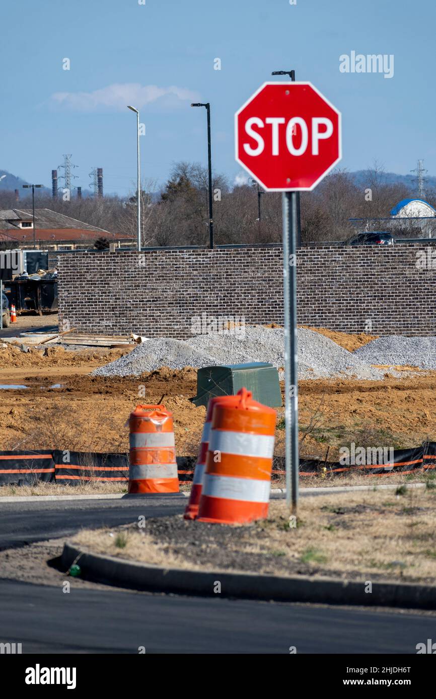 Vertical shot of a stop sign and orange and white traffic barrels at new road construction. Stock Photo