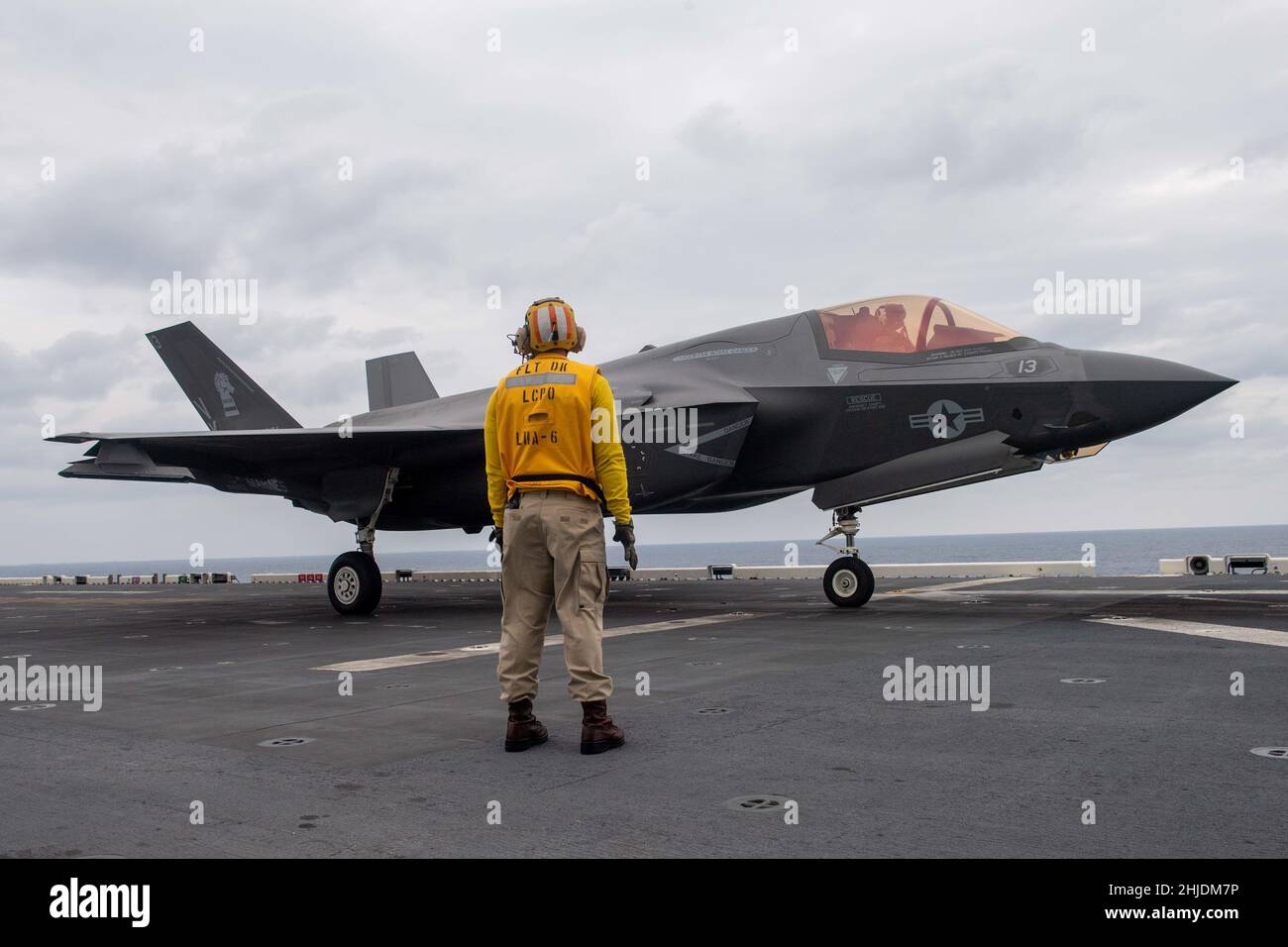 EAST CHINA SEA (Jan. 27, 2022) Aviation Boatswain’s Mate (Handling) 2nd Class Travion Humphrey, from Sacramento, Calif., assigned to the forward-deployed amphibious assault ship USS America (LHA 6), spots an F-35B Lightning II fighter aircraft from the 31st Marine Expeditionary Unit (MEU) on the ship’s flight deck. America, flag ship of the America Amphibious Ready Group, along with the 31st MEU, is operating in the U.S. 7th Fleet area of responsibility to enhance interoperability with allies and partners and serve as a ready response force to defend peace and stability in the Indo-Pacific reg Stock Photo