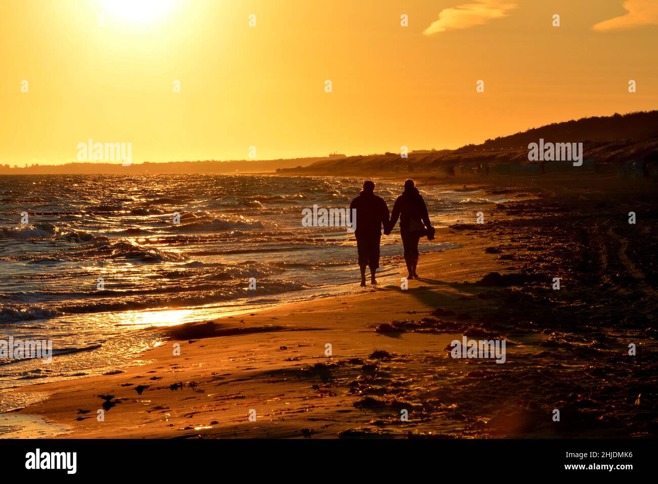Silhouette of couple walking on beach at sunset holding hands ...