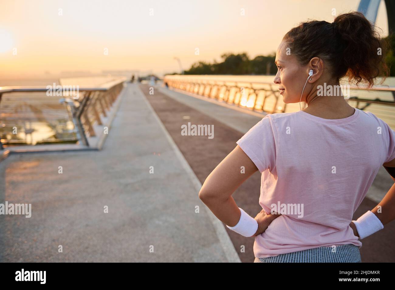 Rear view of a pretty athletic woman, female runner athlete, standing ...