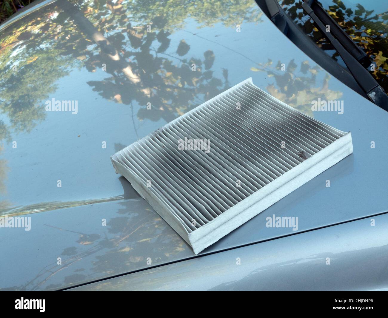 Removed dirty air filter is on the hood of the car. Changing the used