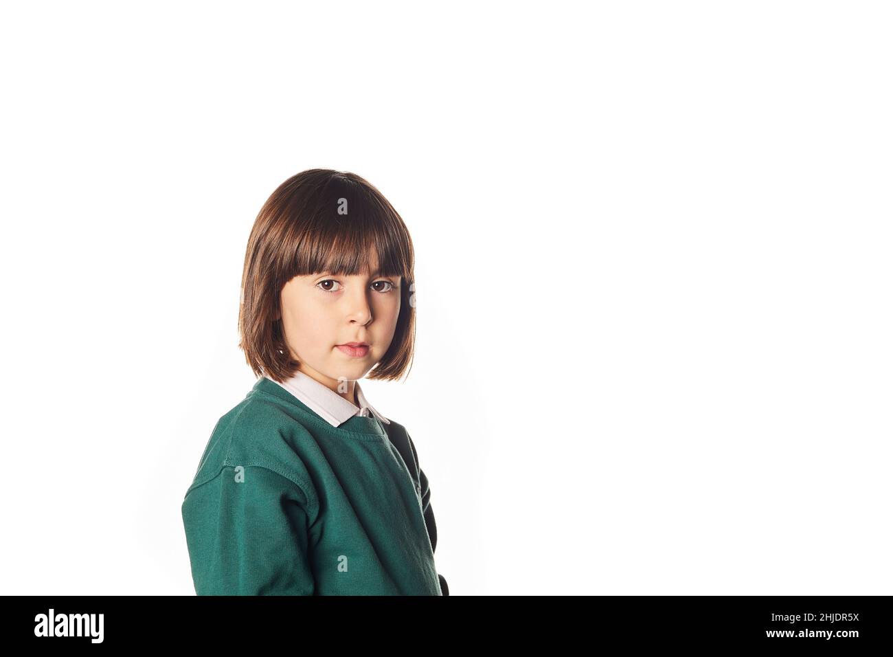 portrait of a 5-year-old girl in a school uniform on a white background with a neutral expression and looking at the camera. Who returns to junior sch Stock Photo