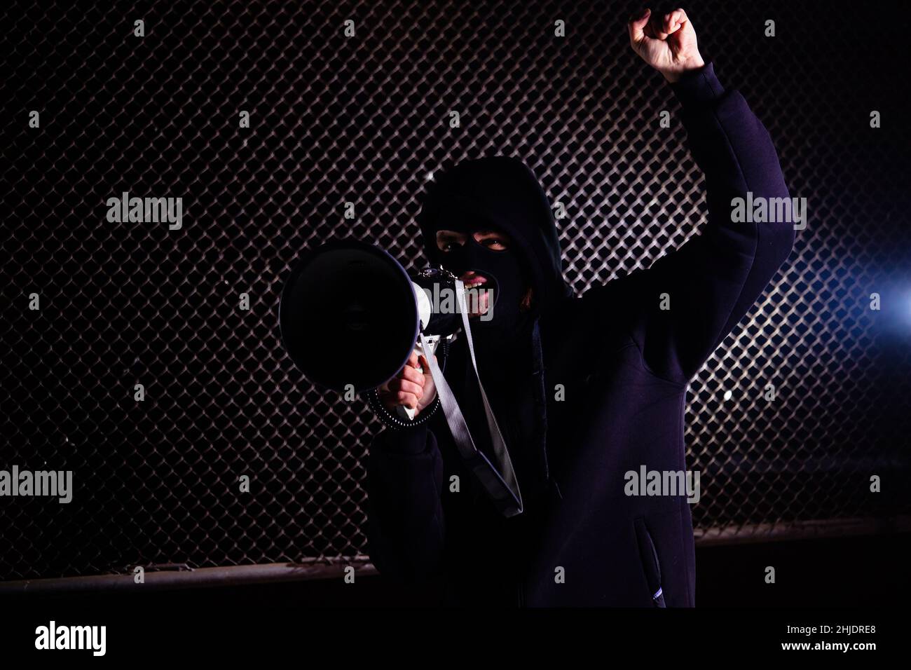 Angry masked man is shouting into the megaphone. Stock Photo