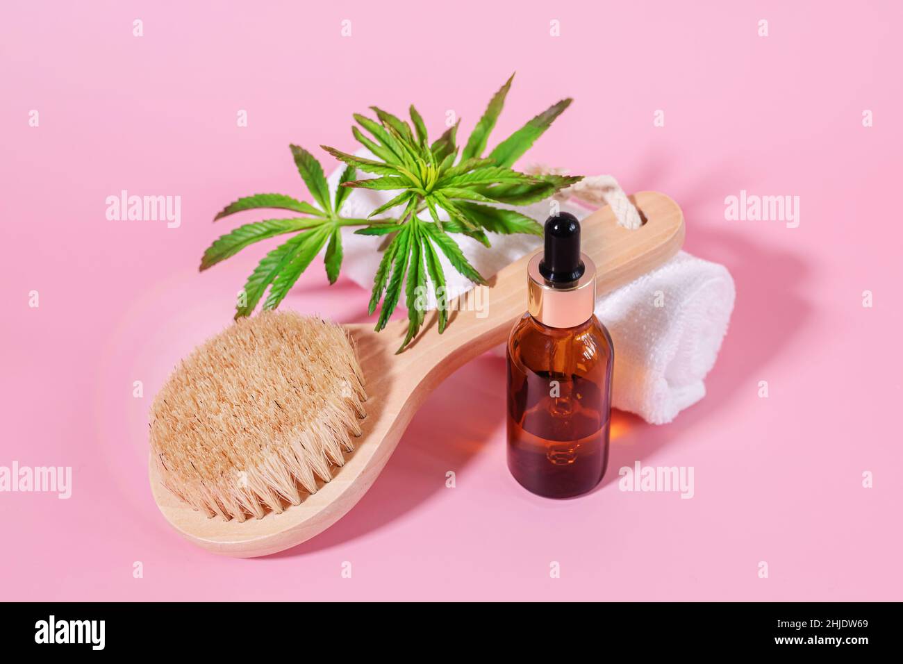 Black glass unbranded bottles of cosmetic oil and cannabis essential oil and a wooden facial cleansing brush with natural bristles. Natural skin care Stock Photo