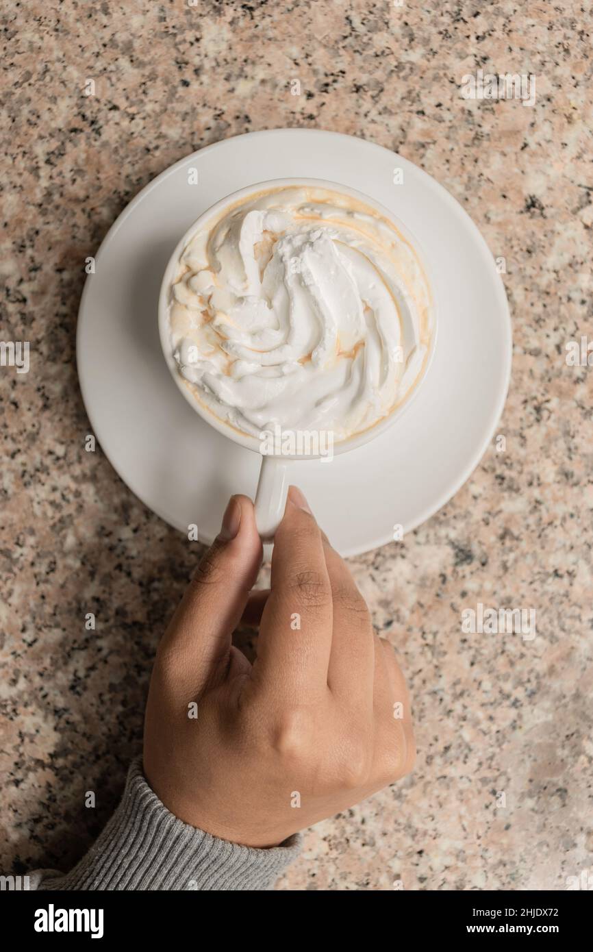 delicious cup of coffee with cream, details of the hands holding the