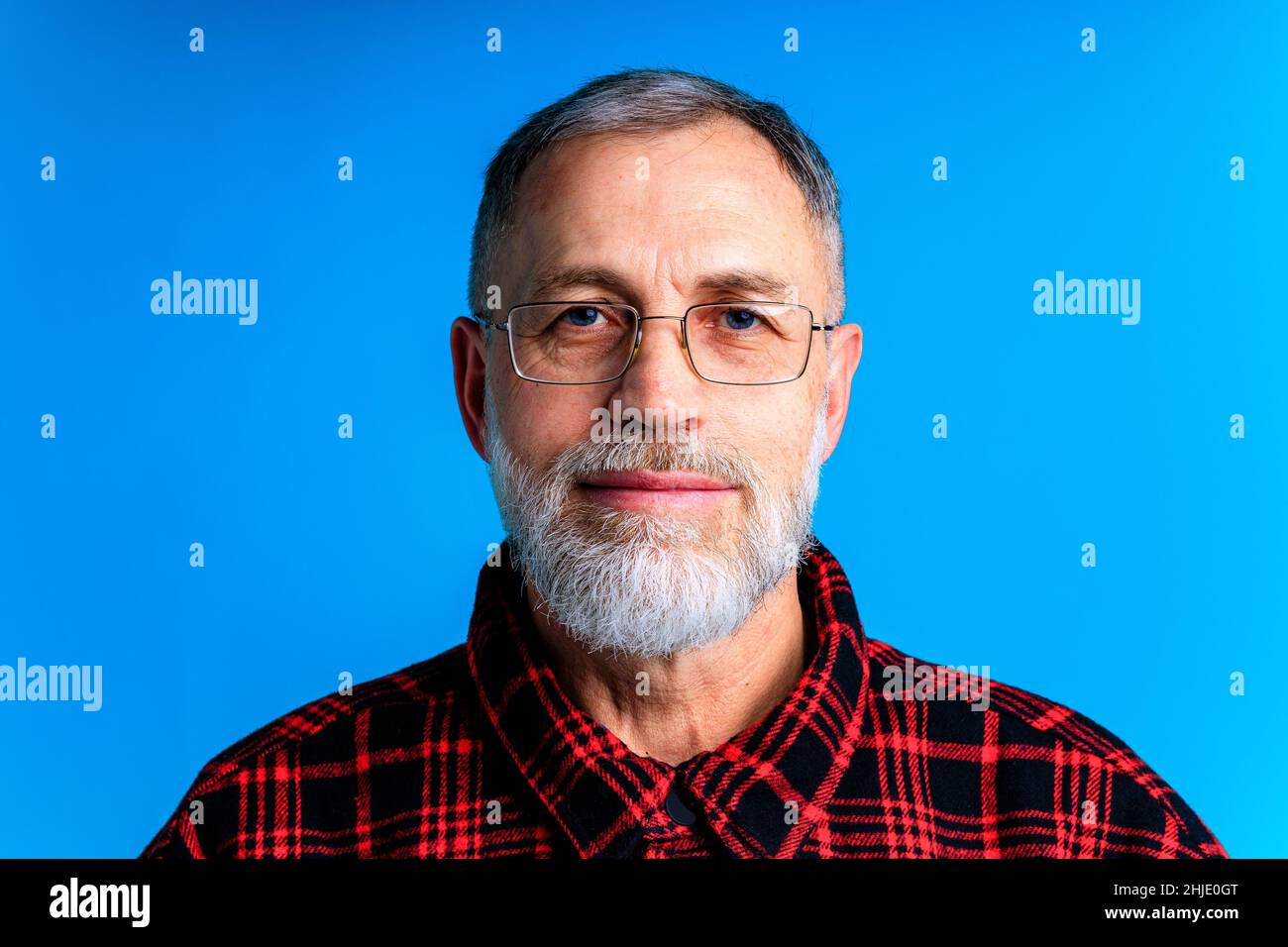 Happy mature man in glasses isolated on blue studio background looking , eyes vision Stock Photo