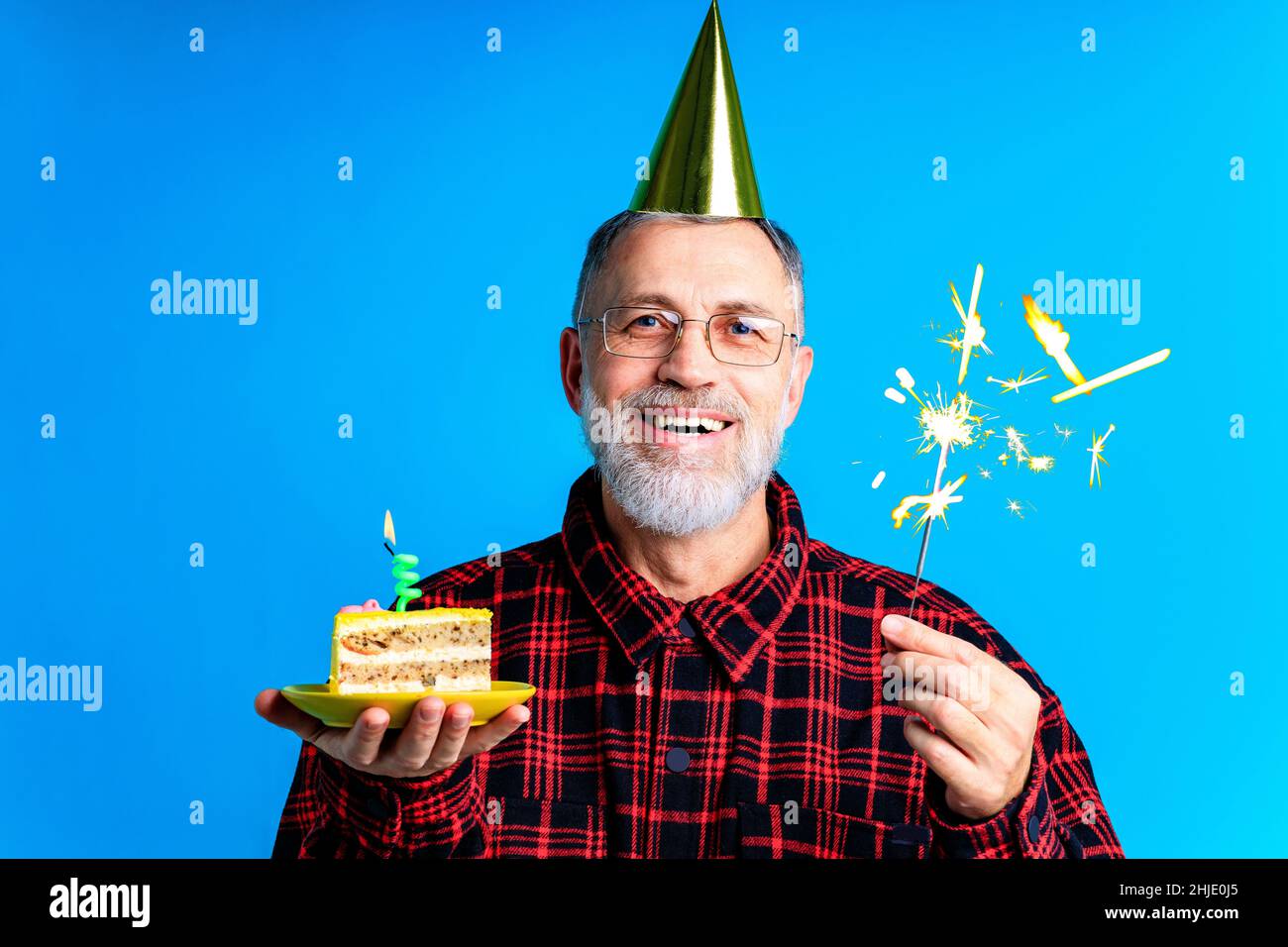 man wearing birthday hat with cake isolated on bright blue colour background, studio portrait Stock Photo