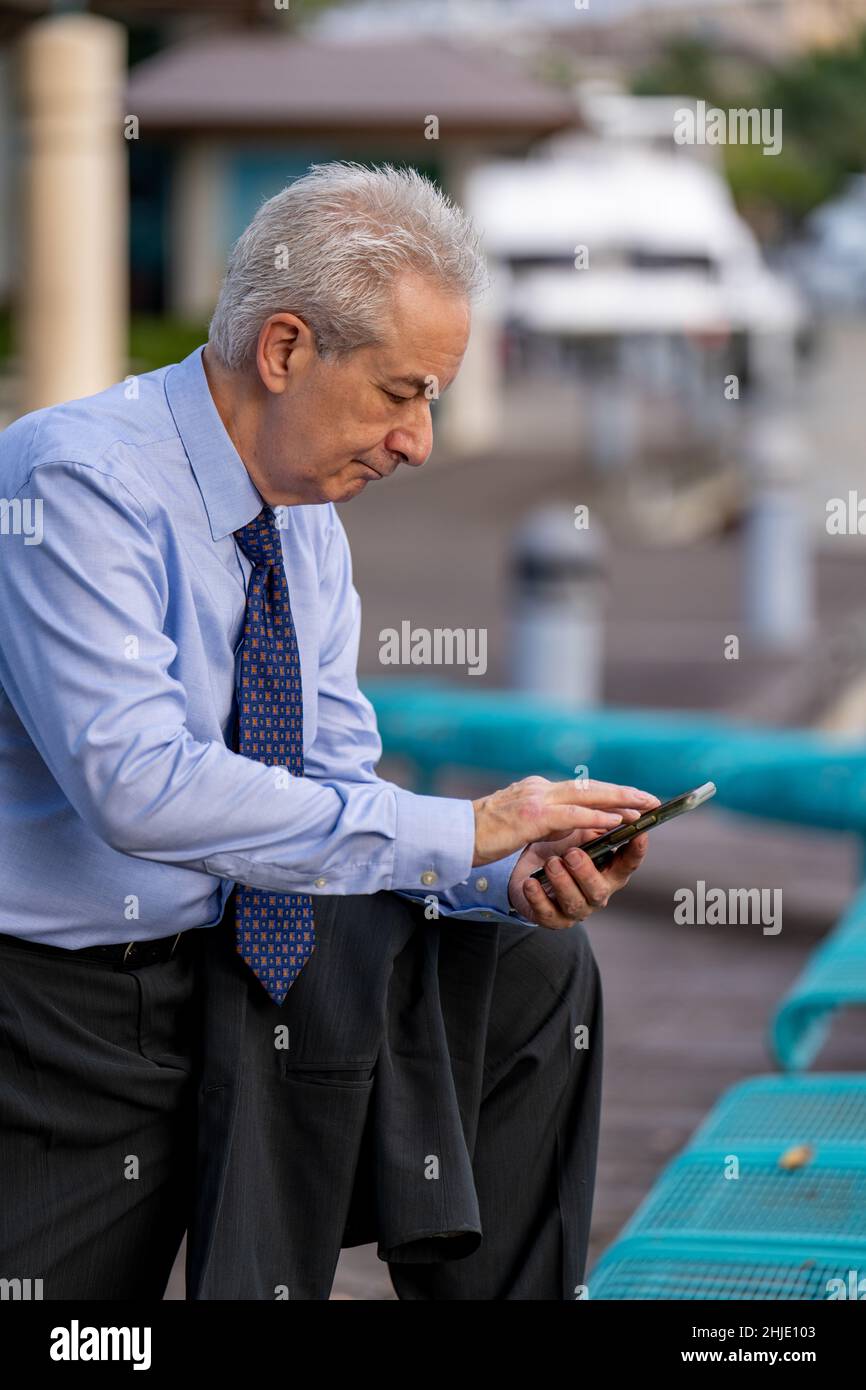 Mature businessman in a blue shirt sending messages on his smart phone Stock Photo