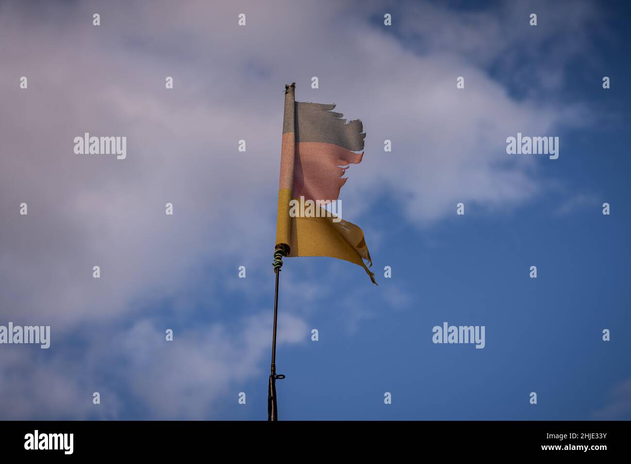 A torn German flag with clouds in the background, seen near Klein Kubitz, Mecklenburg-Western Pomerania, Germany Stock Photo