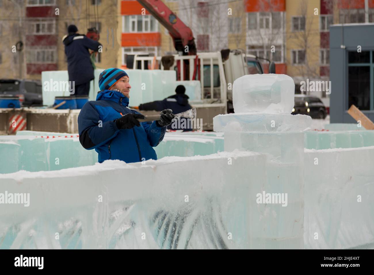 A sculptor carves a round ice ball out of a block of ice with a chisel ...