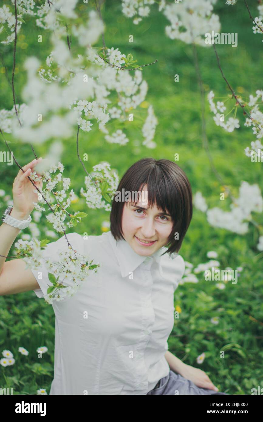 Happy woman sitting in the spring cherry garden Stock Photo - Alamy