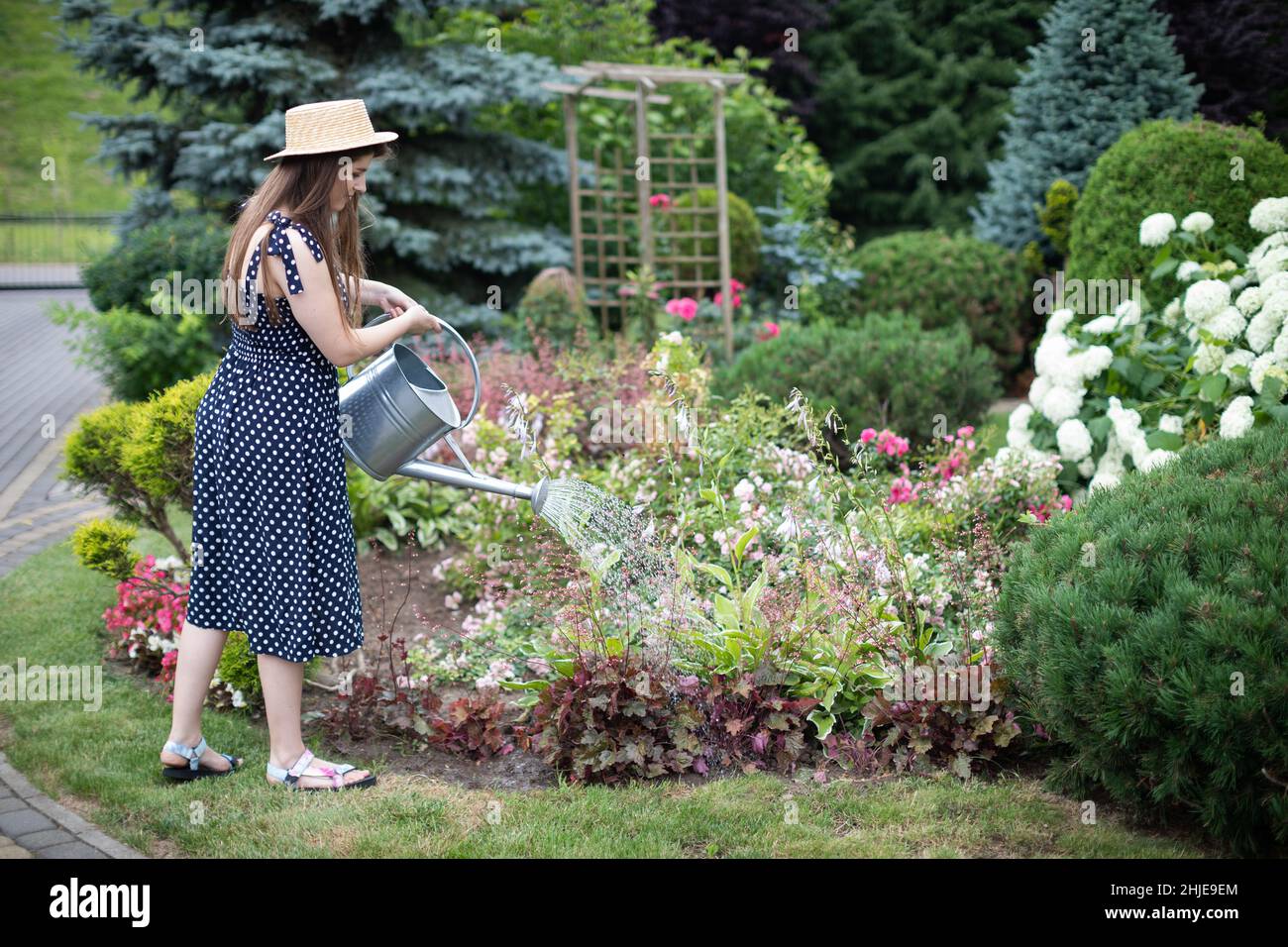 A young girl waters the flowers in her garden with a watering can Stock ...