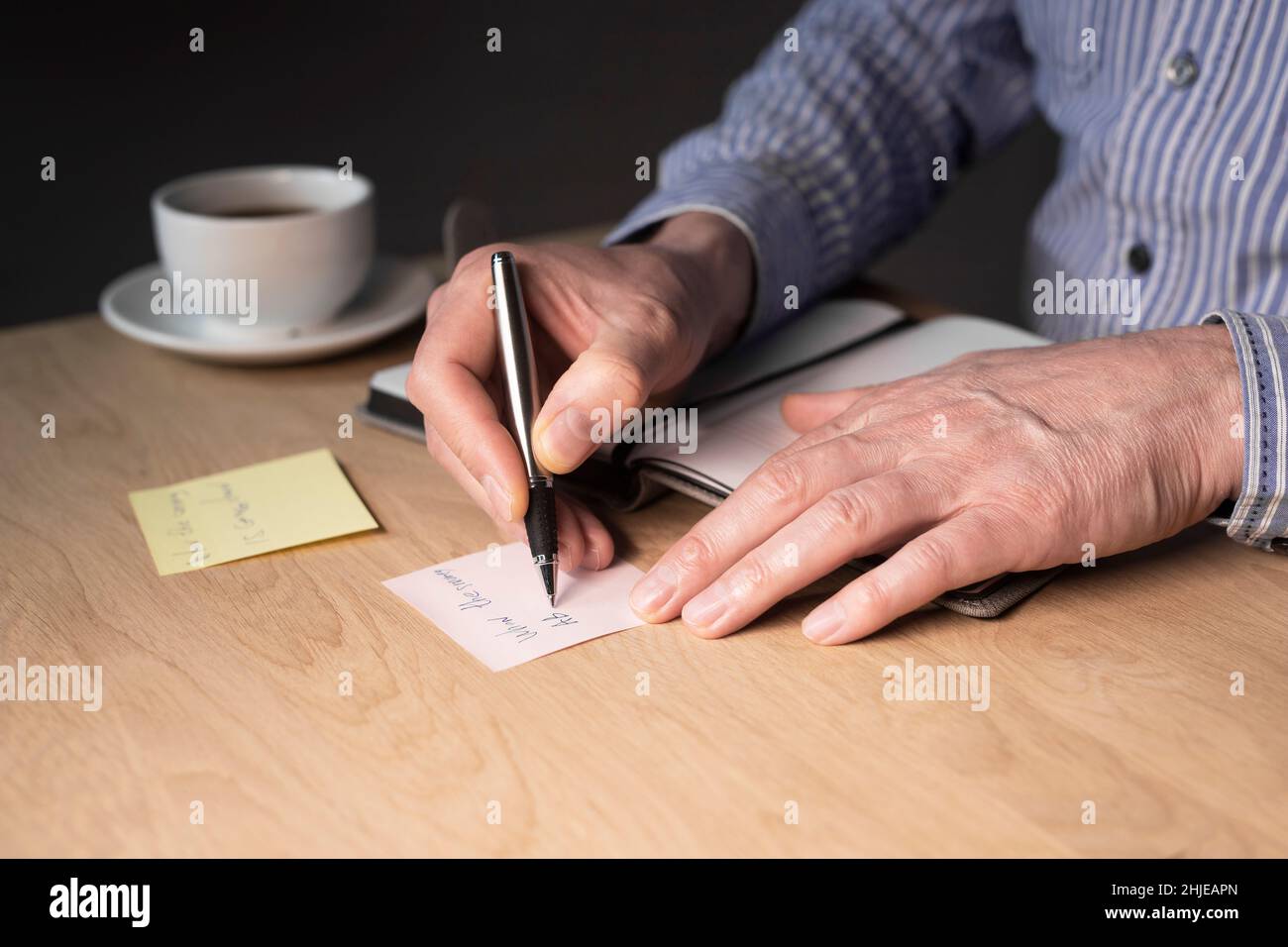 Businessman hands writing memo notes or reminder on sticker at office desk. Stock Photo