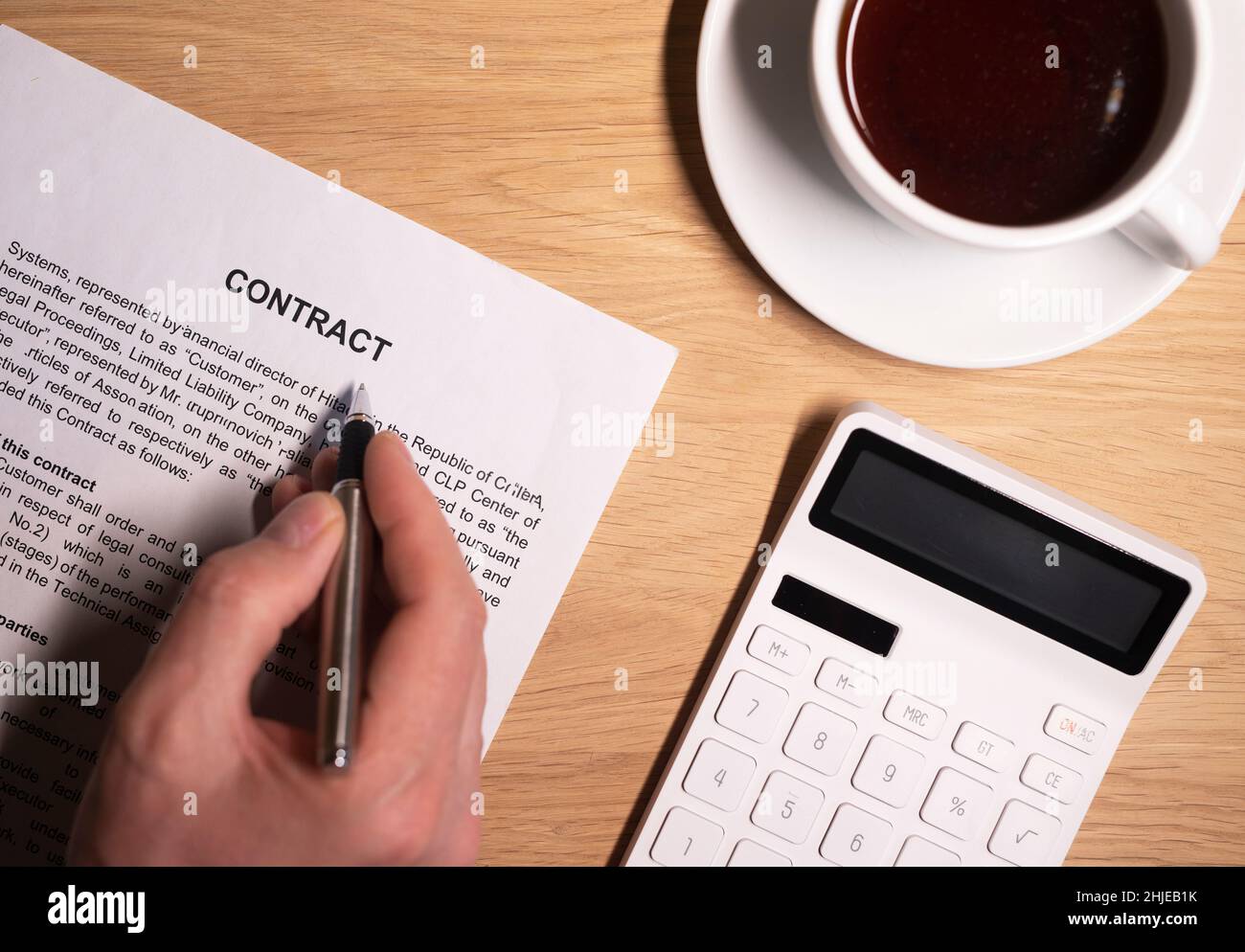 Male hand over legal contract with coffee cup and calculator on wooden
