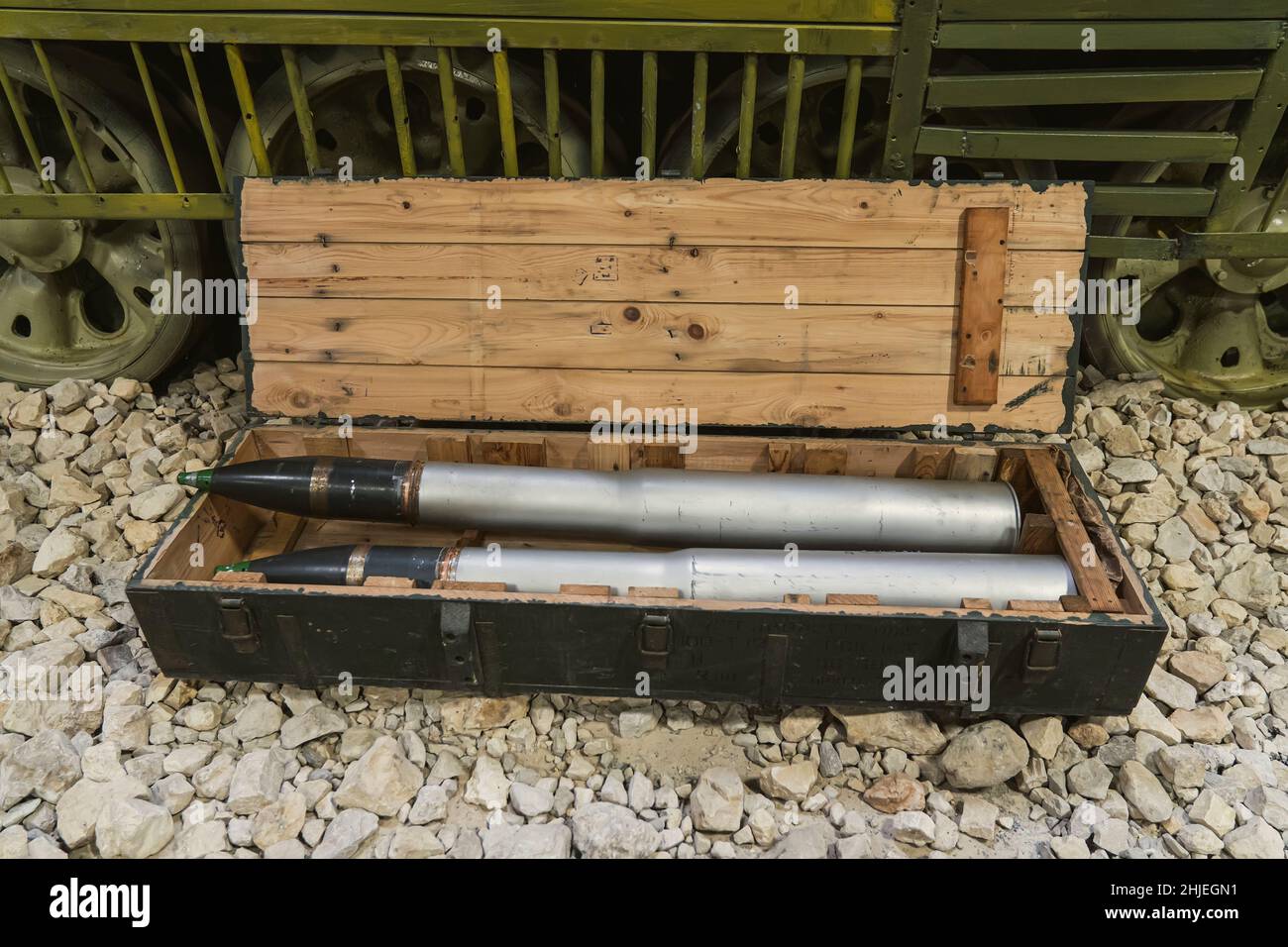 Shells for the tank in a green wooden box on the rocks near the tank. Supply of military ammunition. Stock Photo