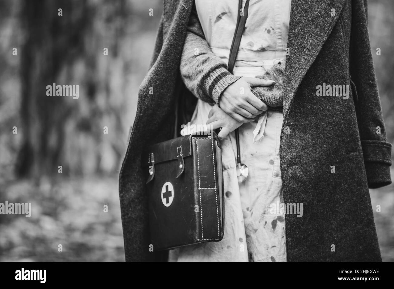 Re-enactor Wears Historical German Nurse Paramedic Of World War II Uniform With First Aid Kit. Photo In Black And White Colors. WWII WW2 Stock Photo
