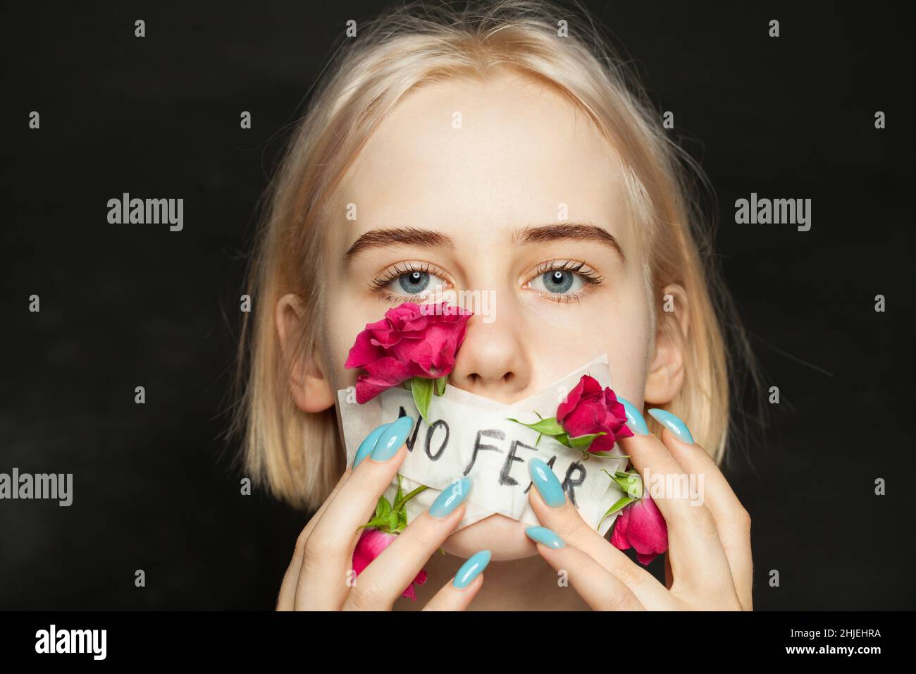 Portrait of beautiful blonde teen girl with patch and flowers on her mouth. Awkward age, growing up and domestic violence concept Stock Photo