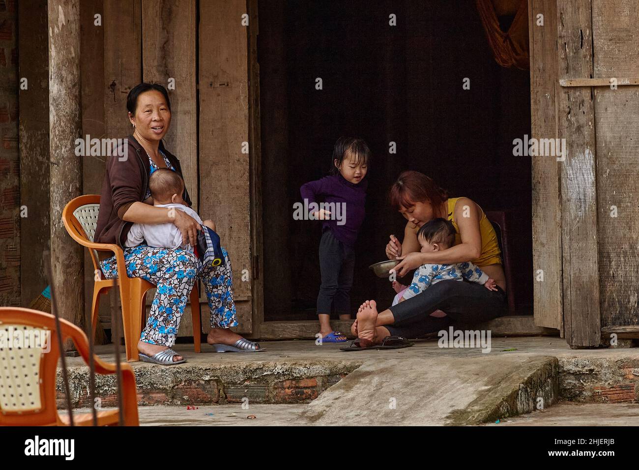 Grandmother, mother and three children a typical small Vietnamese family sits on the threshold