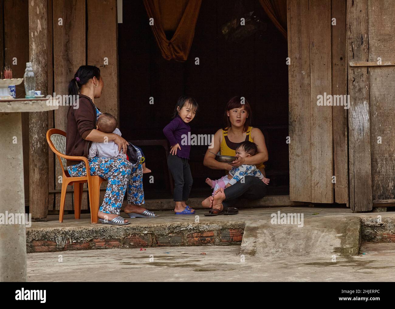 Grandmother, mother and three children a typical small Vietnamese family sits on the threshold