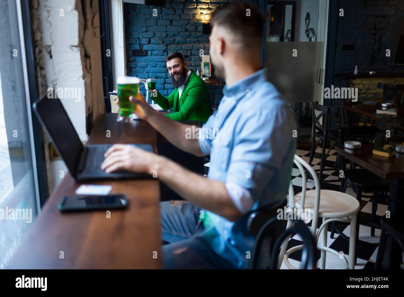 Two friends cheering with green beers on a safe distance Stock Photo