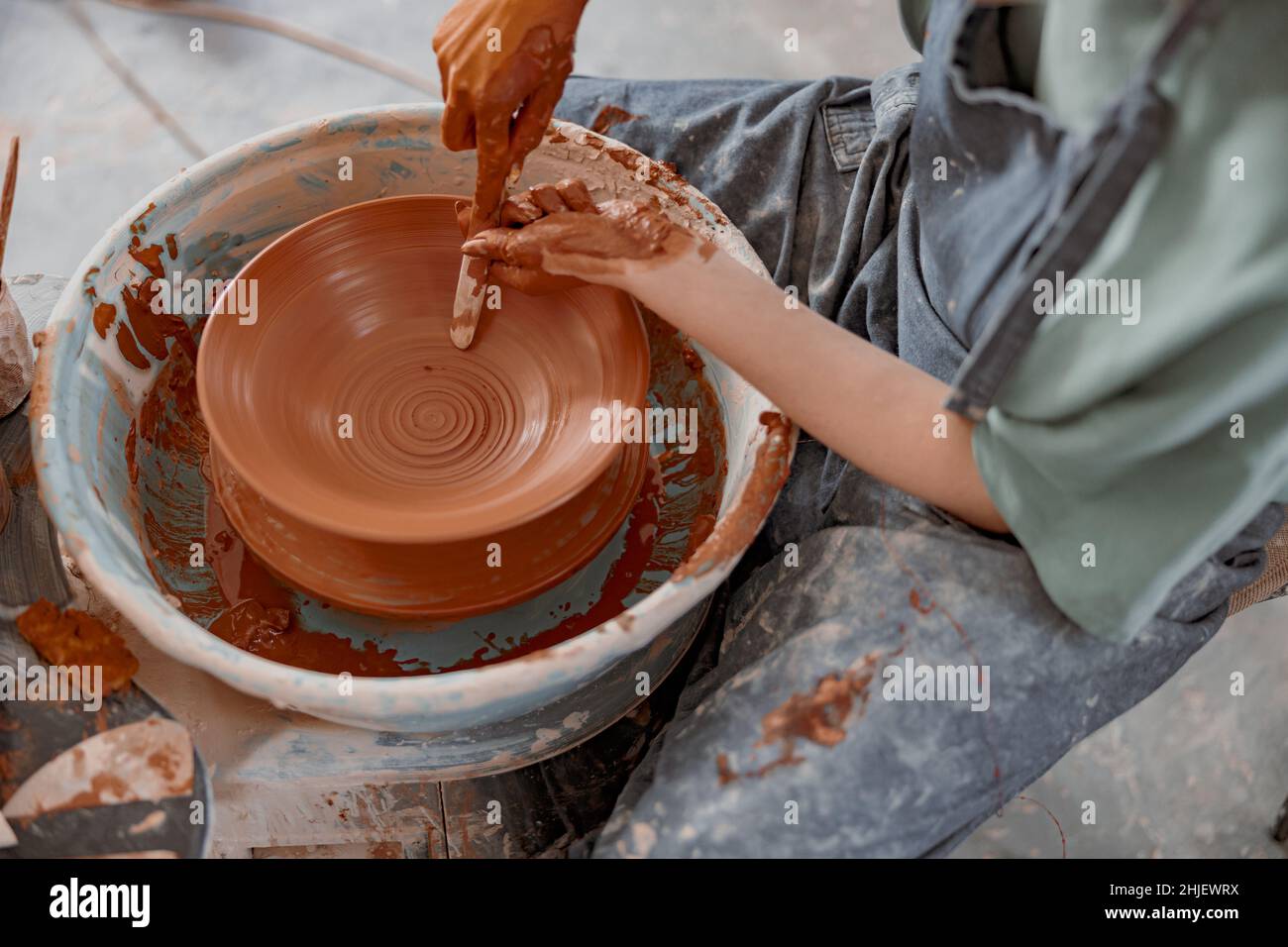 Young potter working on potter wheel in workroom Stock Photo