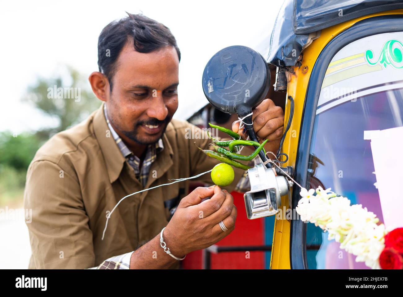 Focus on chilli, auto driver tying chilli and lemon to auto rickshaw ...