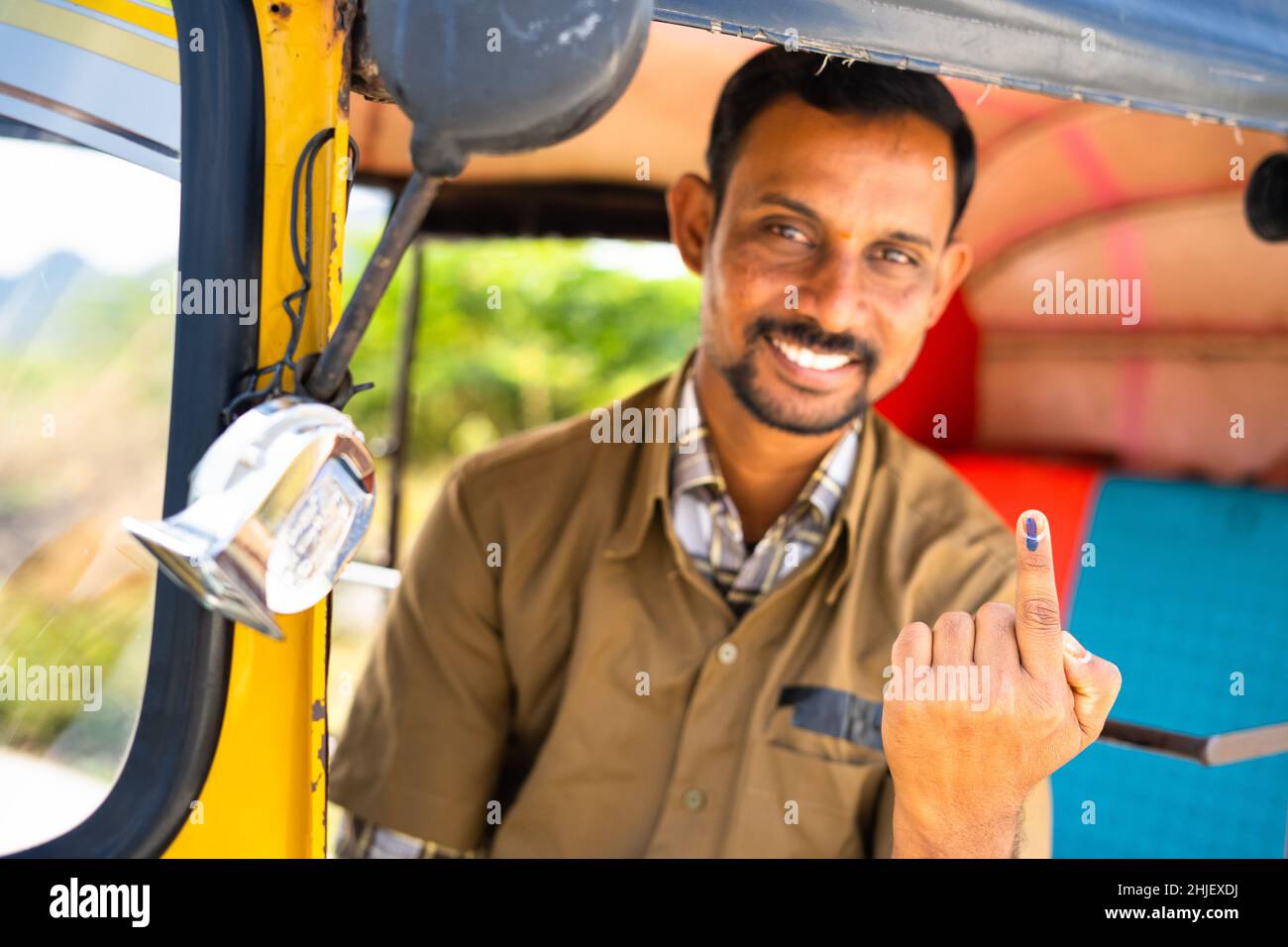 Focus on Finger, Smiling auto driver showing Ink marked finger after voting in election by looking at camera - concept of democracy, Indian election Stock Photo