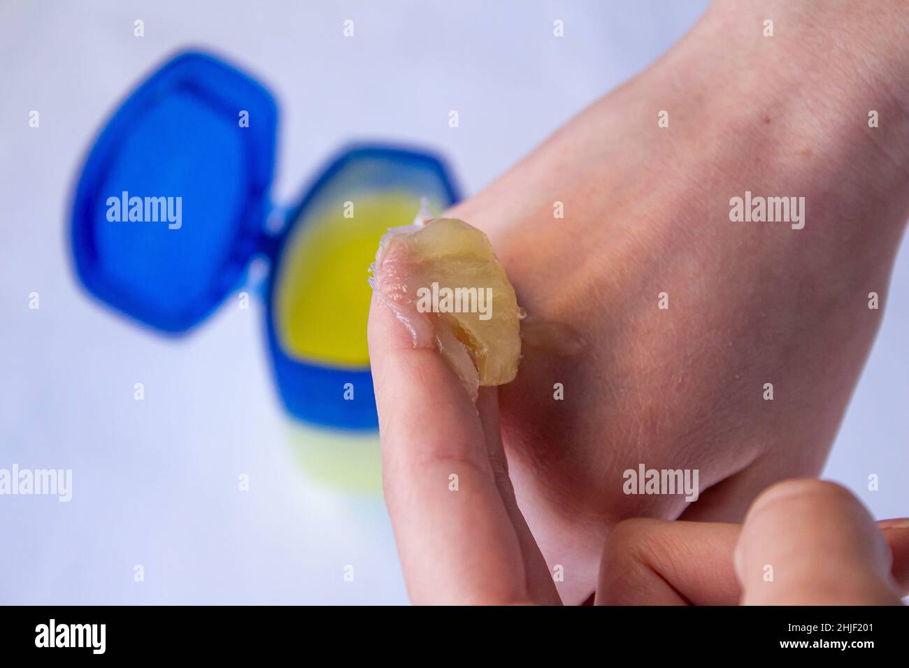 Woman using petroleum jelly. Young girl doing skincare with moisturizing cream. Stock Photo
